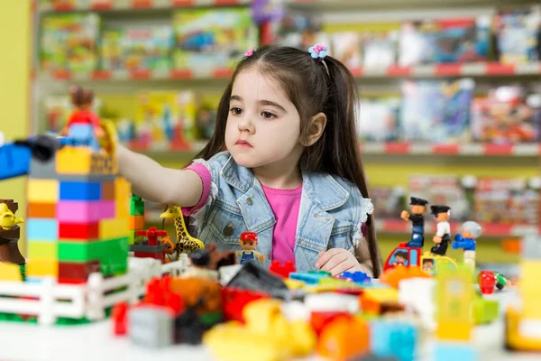Kleines Mädchen spielt im Laden mit Bauklötzen. — Stockfoto