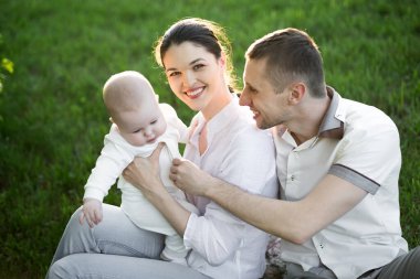 Portre Güzel Anne, Baba ve Bebek açık havada. Mutlu bir aile yaz çayırında.