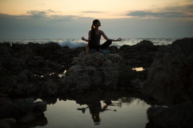 Kafkasyalı kadın okyanus kıyısında yoga yapıyor..