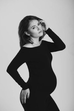 Beyaz arka planda hamile bir kadının siyah beyaz fotoğrafı. Siluet