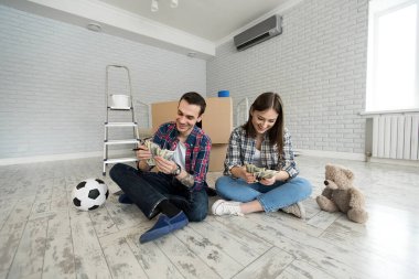 Genç çift yeni dairede yerde otururken para sayıyor..