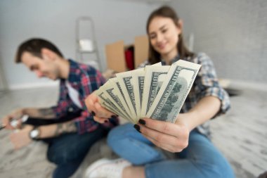 Genç çift yeni dairede yerde otururken para sayıyor..