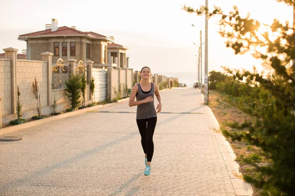 Ung sportig kvinna springer i staden vid solnedgången. — Stockfoto
