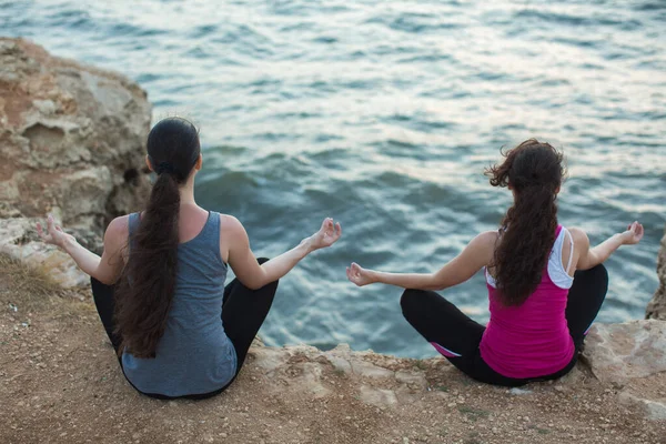 Пара дівчат практикують йогу на пляжі під час заходу сонця — стокове фото
