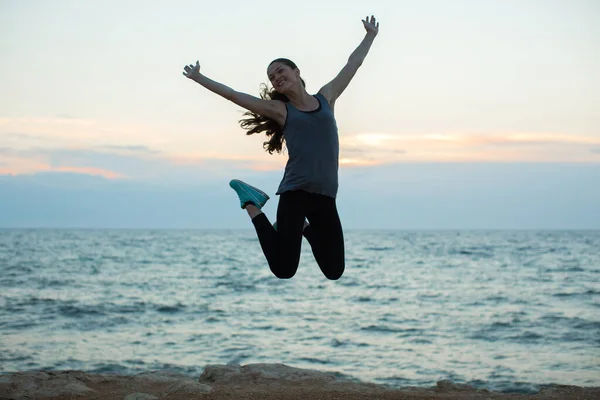 Спортивна дівчина стрибає на пляжі на заході сонця . — стокове фото