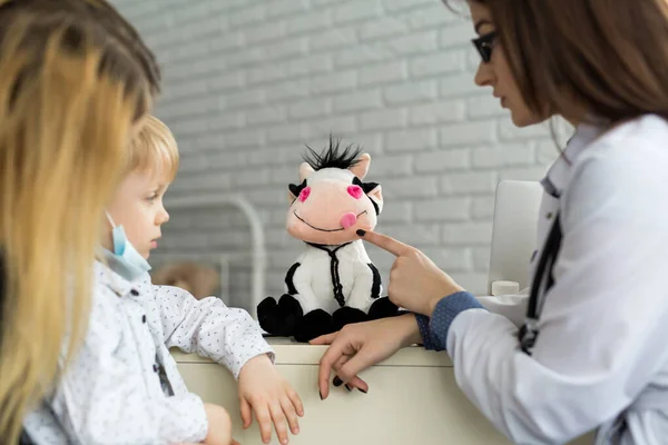 Ein Junge spielt Arzt mit einem Kuhspielzeug. — Stockfoto