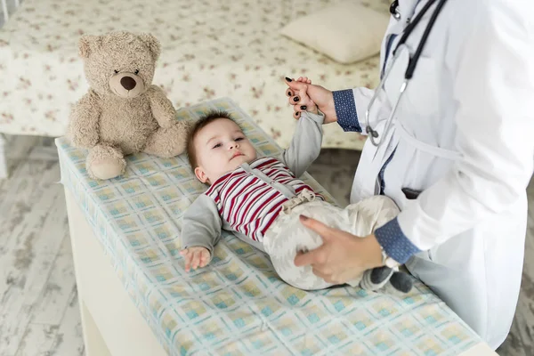 Ein Kinderarzt untersucht ein Baby auf dem Bett. — Stockfoto