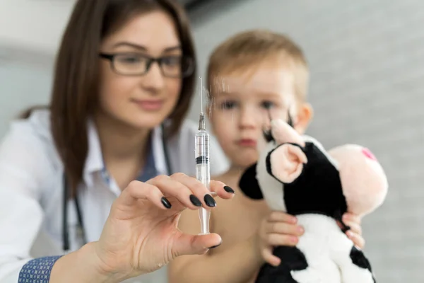 Kinderarzt spielt vor der Spritze mit dem Jungen — Stockfoto