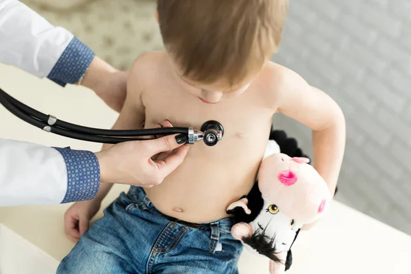 Médico pediatra médico general profesional vestido de uniforme blanco escuchar el sonido del pulmón y el corazón del paciente infantil con estetoscopio —  Fotos de Stock
