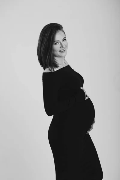 Foto en blanco y negro de una mujer embarazada sobre un fondo blanco. Silueta —  Fotos de Stock