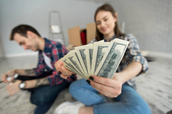 молодая пара подсчитывает деньги, сидя на полу в новой квартире
.
