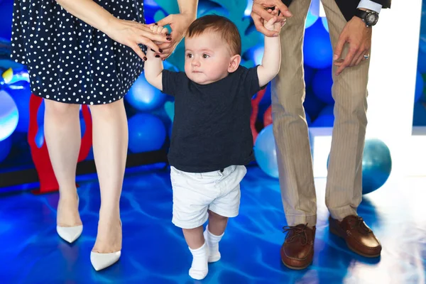 Kleine jongen houdt de hand van zijn vader en moeder vast en probeert de eerste stappen te zetten — Stockfoto