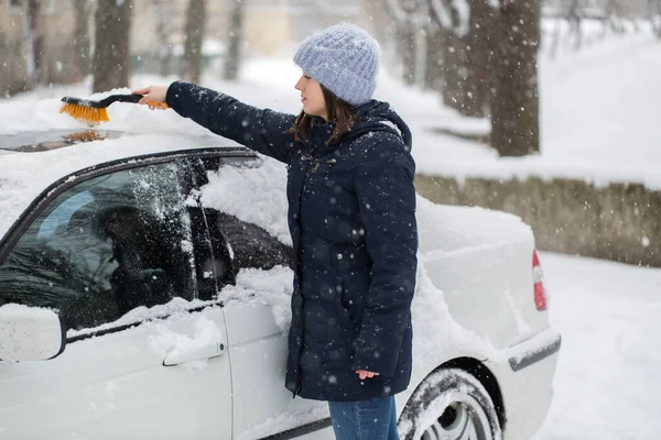 Mulher limpando neve do carro no inverno . — Fotografia de Stock