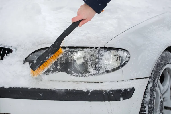 Mulher limpando neve do carro no inverno. Farol do carro — Fotografia de Stock