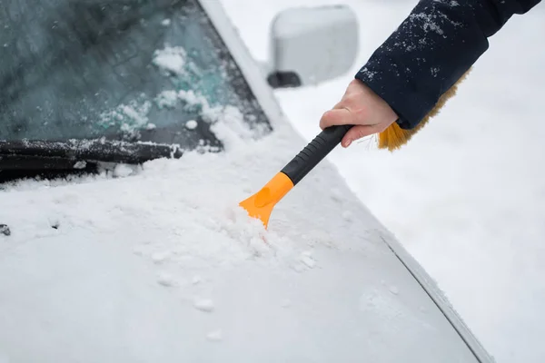 Mulher limpando neve do carro no inverno . — Fotografia de Stock