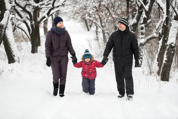 A young family with a child walking through a snow-covered forest. — Stock Photo, Image