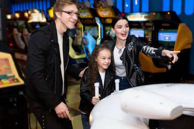 Aile annesi, babası ve kızı lunaparktaki bilgisayar makinelerinde oyun oynuyorlar. Çocuklar ve yetişkinler kumar makinelerinde oynarlar, alışveriş merkezinde eğlenirler.