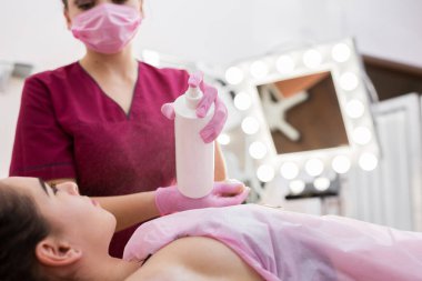 Saçları dökülmüş genç bir kızın koltukaltı, bir güzellik salonunda saç çıkarma prosedürü. Güzellik uzmanı genç bir kadın için koltuk altını titretiyor. Koltuk altının şeker macunuyla doldurulması.