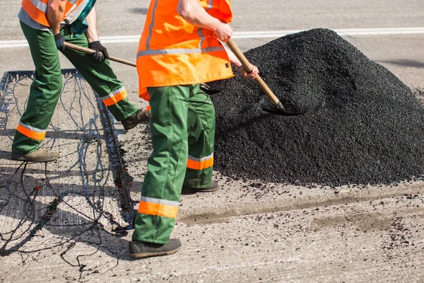 Repair of roads, highways and sidewalks. Patching. Working with a shovel falls asleep in the pit — Stock Photo, Image