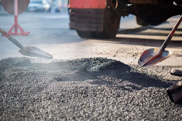 Giovane costruttore su asfaltatrice durante lavori di riparazione stradale. — Foto Stock