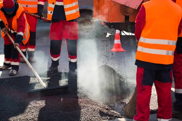 Livellamento dei lavoratori asfalto fresco su un cantiere stradale, edifici industriali e lavoro di squadra . — Foto Stock