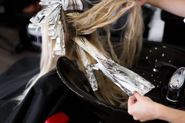Stylist lava a cabeça em um salão de beleza. Cor do cabelo morrendo, folha metálica . — Fotografia de Stock