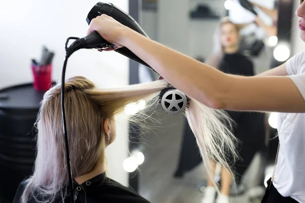 Secagem de cabelo loiro longo com secador de cabelo e escova redonda . — Fotografia de Stock