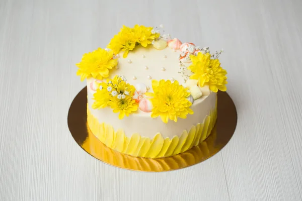 Cake with yellow stains, yellow chrysanthemums and meringue. — Stock Photo, Image