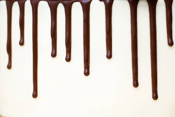 Chocolate drips on the background of white cream. — Stock Photo, Image