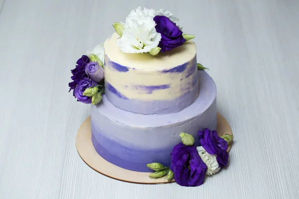 Düğün iki katlı mor pasta ve taze çiçekler. — Stok fotoğraf