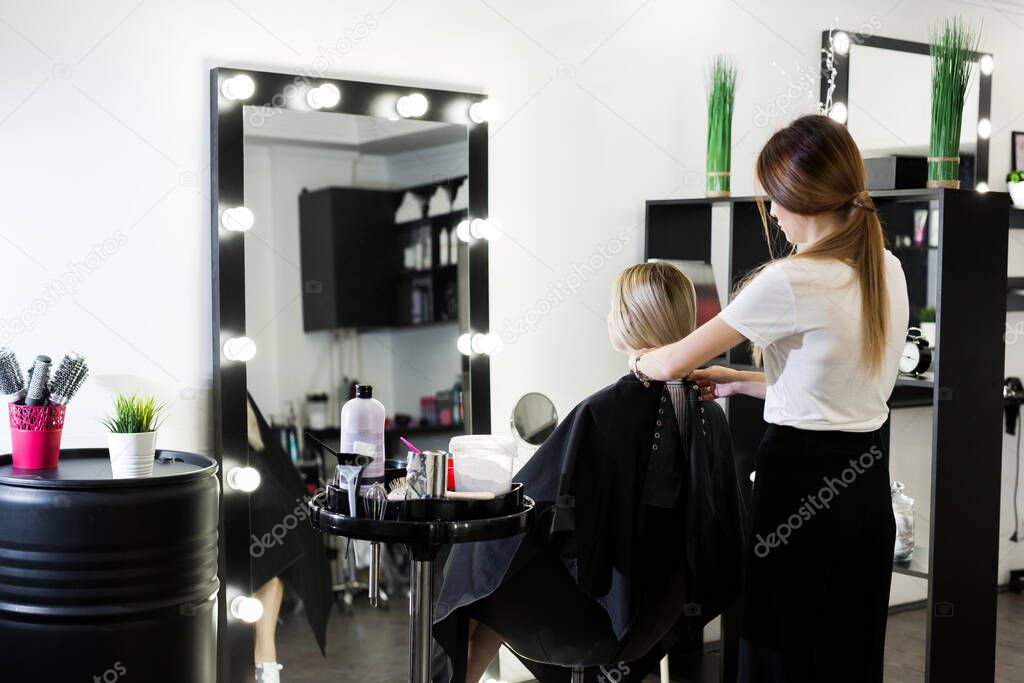 Comb hair. The master in the hairdresser prepares the clients girl to restore the procedures.