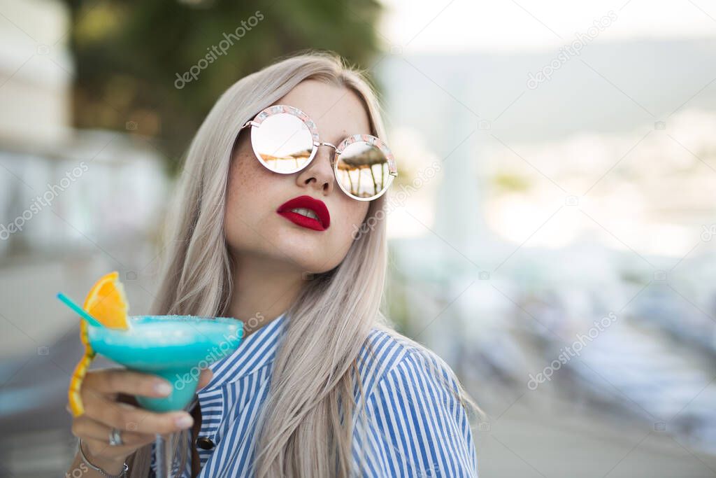 Portrait of a young woman with a cocktail glass at the bar. Beautiful girl enjoying alcoholic cocktail outside.
