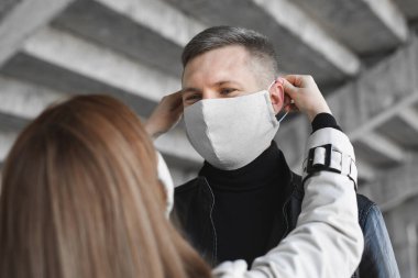 Kadın bir erkeğin yüzüne koruyucu maske takıyor. Coronavirus, covid19
