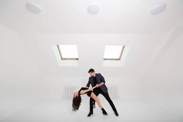 Lindo casal dança bachata no fundo branco no estúdio . — Fotografia de Stock