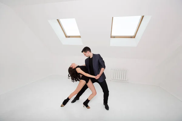 Lindo casal dança bachata no fundo branco no estúdio . — Fotografia de Stock