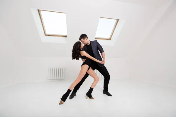 Lindo casal dança bachata no fundo branco no estúdio . — Fotografia de Stock