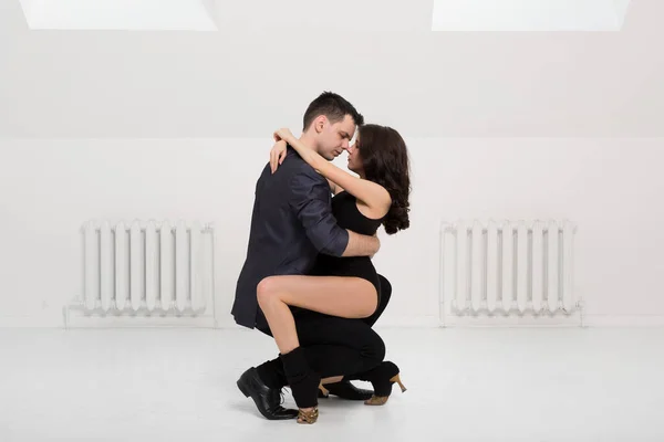 Lindo casal dança bachata no fundo branco no estúdio . — Fotografia de Stock