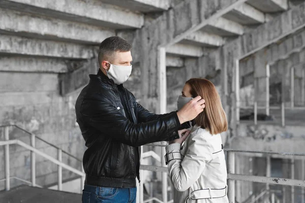 L'uomo mette una maschera protettiva sul viso di una donna. Coronavirus, Covid-19 — Foto Stock