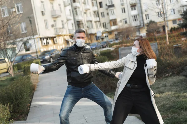 Žena a muž v koronavirovém obličeji maska držet velké role toaletního papíru na ulici a dopřát. — Stock fotografie