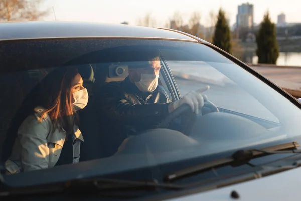 Un hombre y una mujer que usan máscaras médicas y guantes de goma para protegerse de bacterias y virus mientras conducen un automóvil. hombres enmascarados en el coche. coronavirus, covid-19 — Foto de Stock