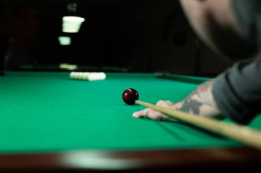 Bilardo topuna bilardo sopasıyla nişan alan bir adam..