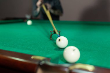 Erkek eli ve Cue kolu bilardo oynuyor ya da yeşil bir bilardo masasında bilardo topu fırlatmaya hazırlanıyor..