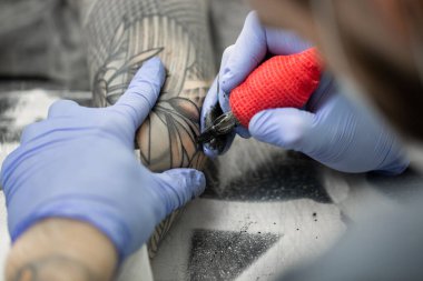 Dövme sanatçısı genç bir kızın eline dövme yapıyor..