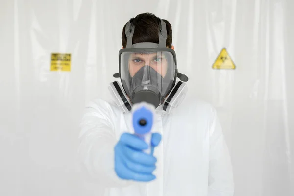 보호용 마스크를 착용하고 있는 의사는 바이러스 증상 이 나타나는지 체온을 확인하기 위해 적외선 이마 온도계를 사용 할 준비가 되어 있습니다. Coronavirus.Thermometer 총 — 스톡 사진