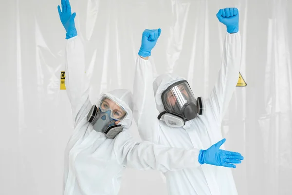 Portraits d'un médecin : un homme et une femme en combinaison de protection et respirateurs, portant des gants, s'amusant pendant la quarantaine. Covid-19 — Photo