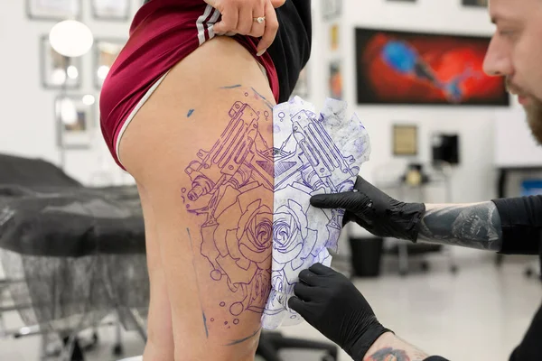 タトゥーアーティストはタトゥーサロンで女性の足にタトゥースケッチを転送します. — ストック写真
