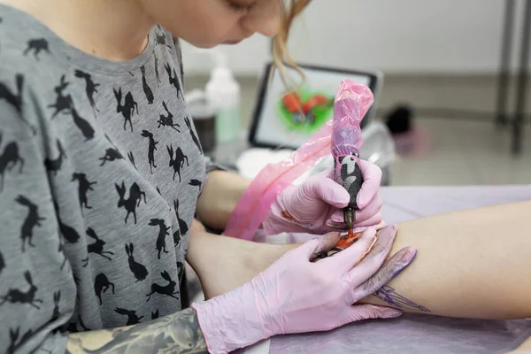 Professional tattoo artist which making tattoo on the leg of a young girl. Hands of a tattoo artist. Tattooist makes a tattoo. — Stock Photo, Image