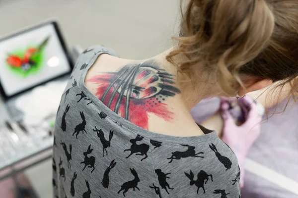 若い女の子の足にカラータトゥーを入れる女性アーティストのクローズアップ。後方からの眺め. — ストック写真