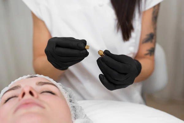Close-up of a beautician doctor in black sterile gloves opens an ampoule with hyaluronic acid before the rejuvenation procedure. — Stock Photo, Image
