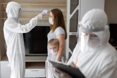 Doktor, evde kızılötesi alın termometresi kullanarak hastanın vücut ısısını ölçün. Coronavirus, covid-19, karantina, yüksek sıcaklık.